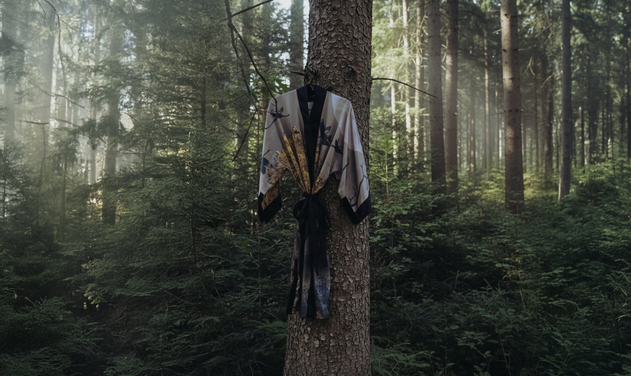Celestial Noir Kimono by KARUMA hanging in the Black Forest, allover crane and botanical print in dusty rose and gold tones