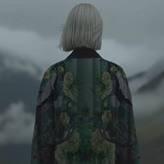 Designer long kimono with rich jade green nature print, modeled in a dramatic cloudy mountain setting